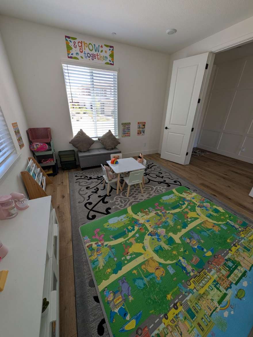 The playroom with the learning table, book shelf, window bench, and play mat