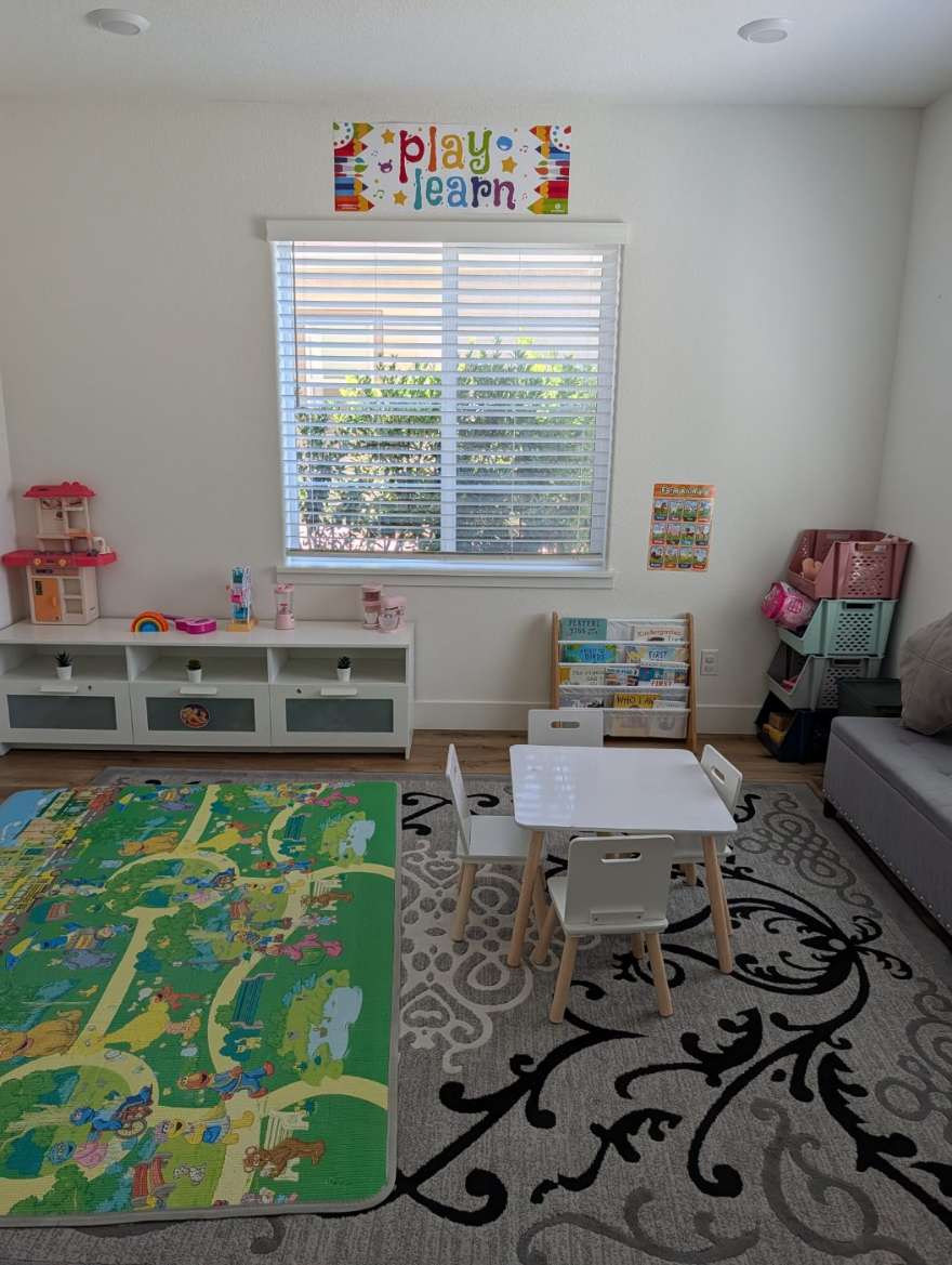 The playroom with the learning table, book rack, play kitchen, and play mat